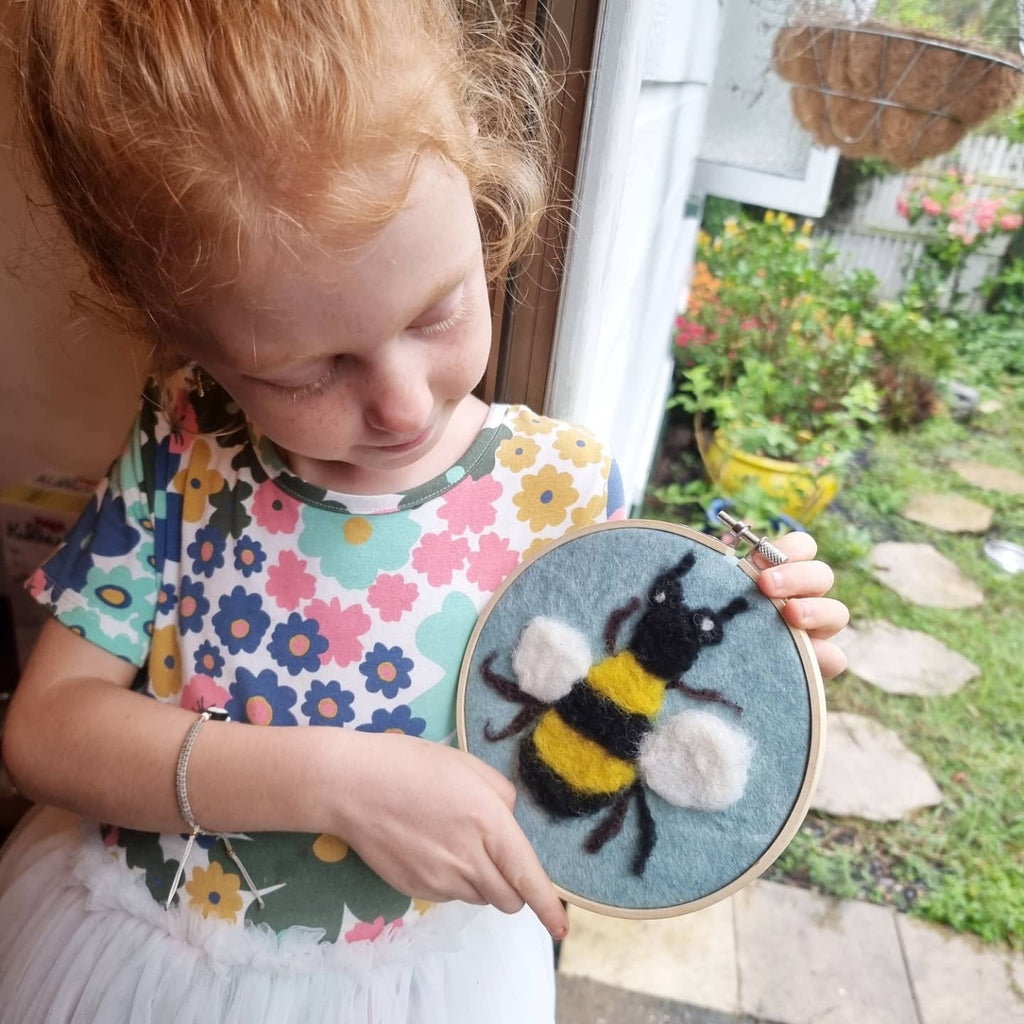 toy shop girl at home with completed Bee in a Hoop Needle Felt Craft Kit