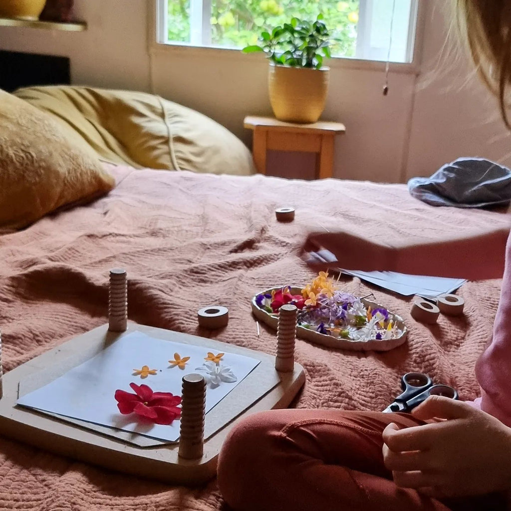 top shop kid pressing flowers using drewart flower press in light-filled room