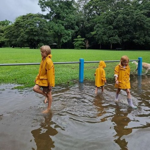 three kids in the park playing in puddle wearing RainKoat Childrens Rain Jackets Yellow