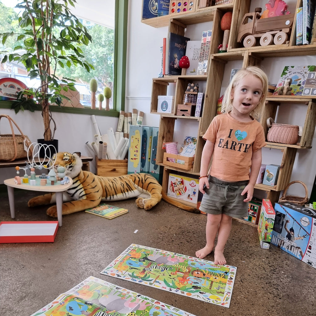 young child completing jungle obersation djeco childrens puzzle surrounded by earth toys stock
