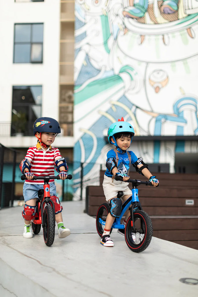 toddlers riding balance bikes red and blue