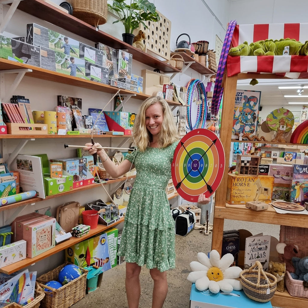 bree at earth toys toy shop cairns, holding rainbow vah target and wooden bow and arrow set