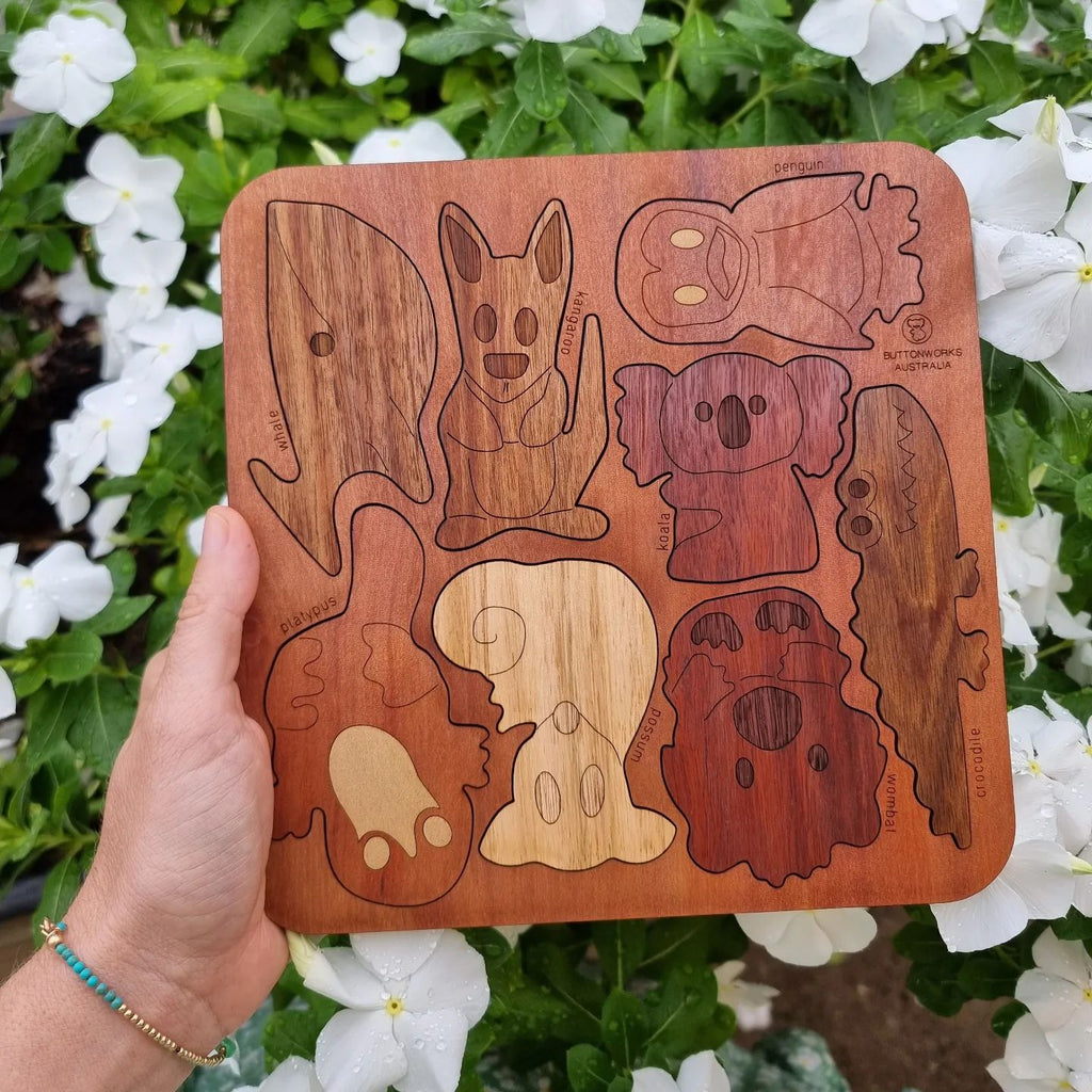 australian animal wooden puzzle made in australia, held in front of white flowers